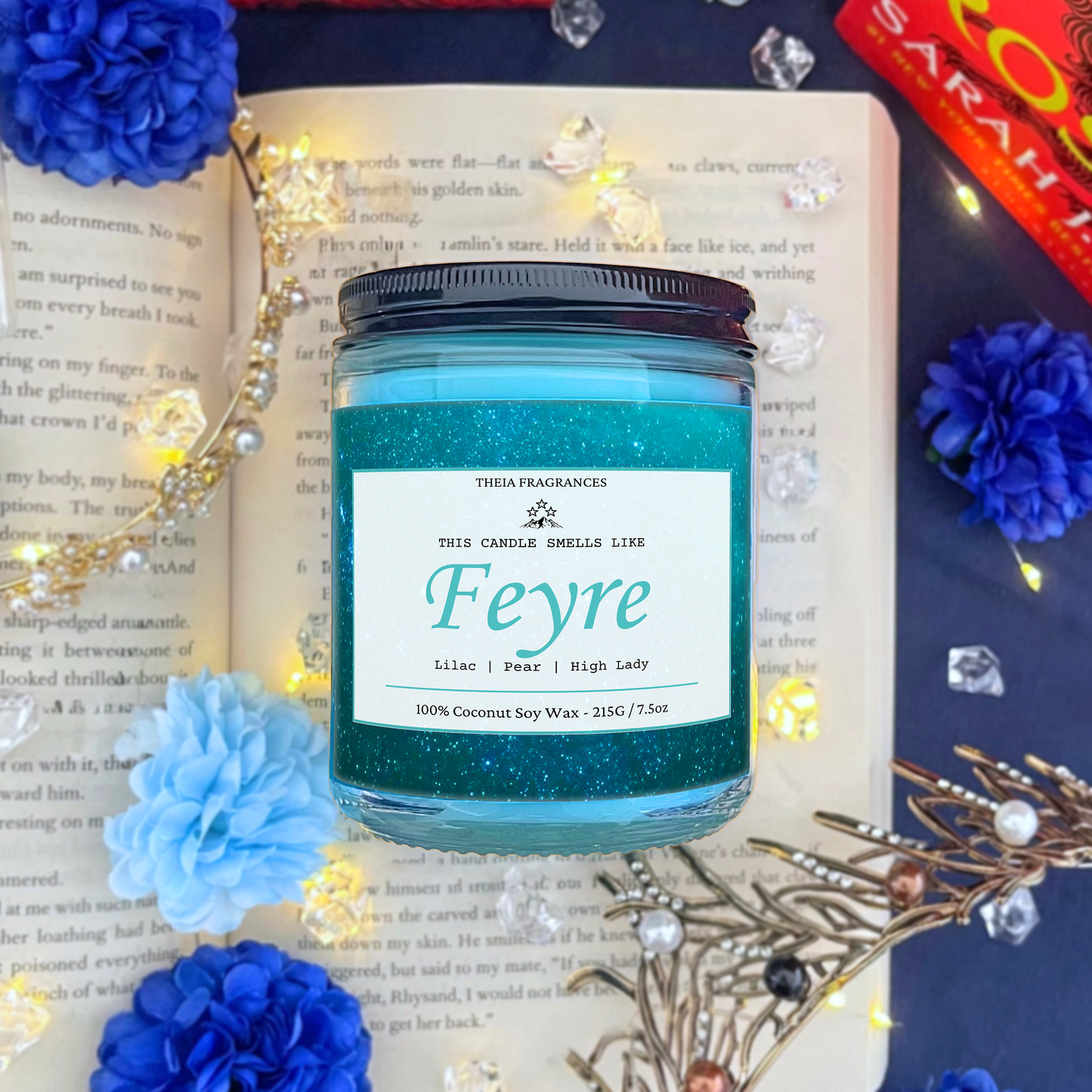 The 'High Lady of the Night Court' coconut soy wax candle by Theia Fragrances is demonstrated in the 215G glass jar with a black lid. The label features a teal galaxy. It is styled on an open book with decorative crystals and flowers.