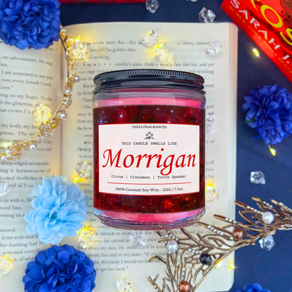 The 'Truth Speaker' coconut soy wax candle by Theia Fragrances is demonstrated in the 215G glass jar with a black lid. The label features a burgundy galaxy. It is styled on an open book with decorative crystals and flowers.